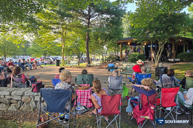 people sitting in lawn chairs and enjoying a concert